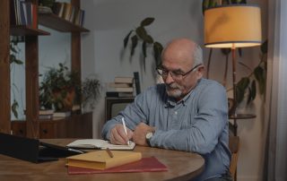 Elderly man writing at a table